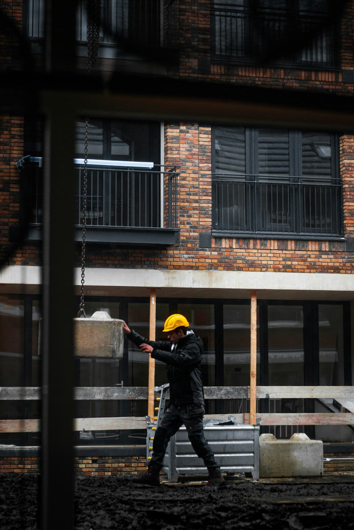 Bouwvakker begeleidt een betonblok bij een Nederlands appartementengebouw